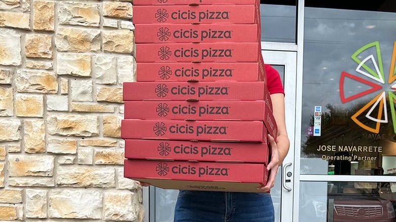 Someone carries multiple Cici's Pizza boxes.