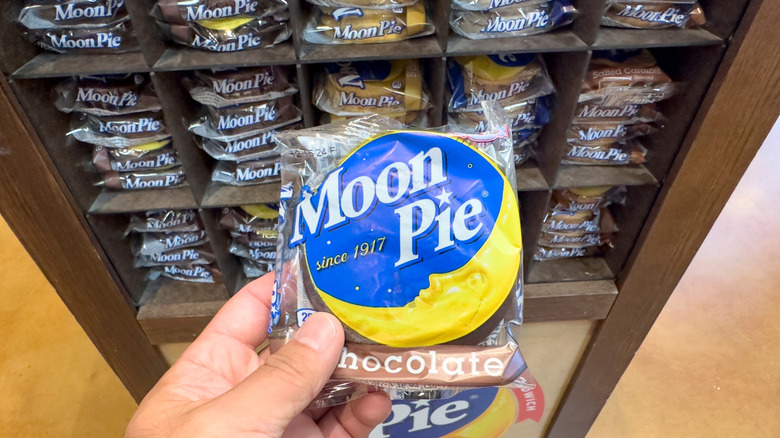 Hand holding an individually-wrapped Moon Pie in front of a display