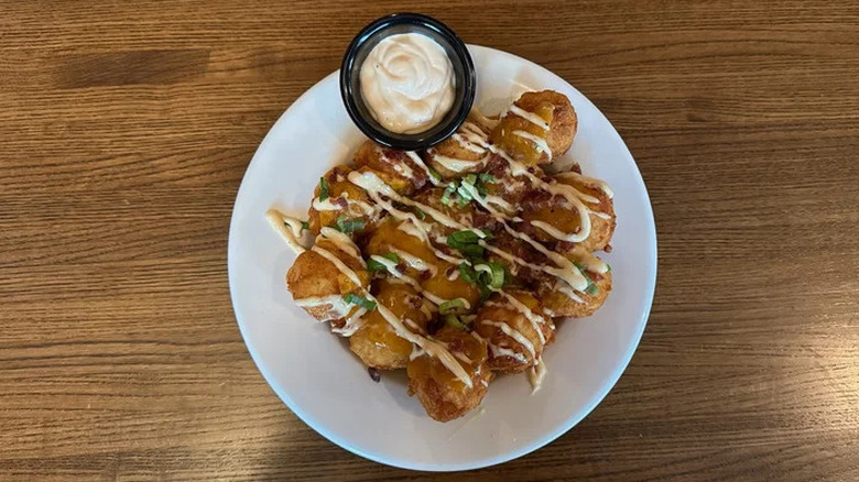 TGI Fridays Loaded Tots with cheese, bacon, and green onion, drizzled with TGI Sauce.