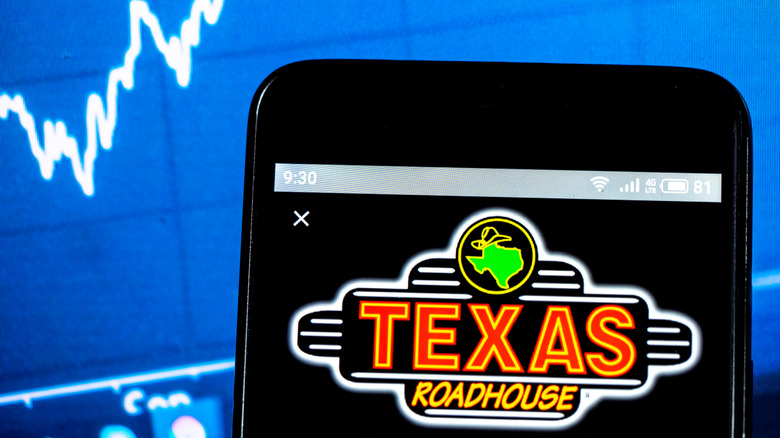 a mobile phone showing the Texas Roadhouse logo on the screen
