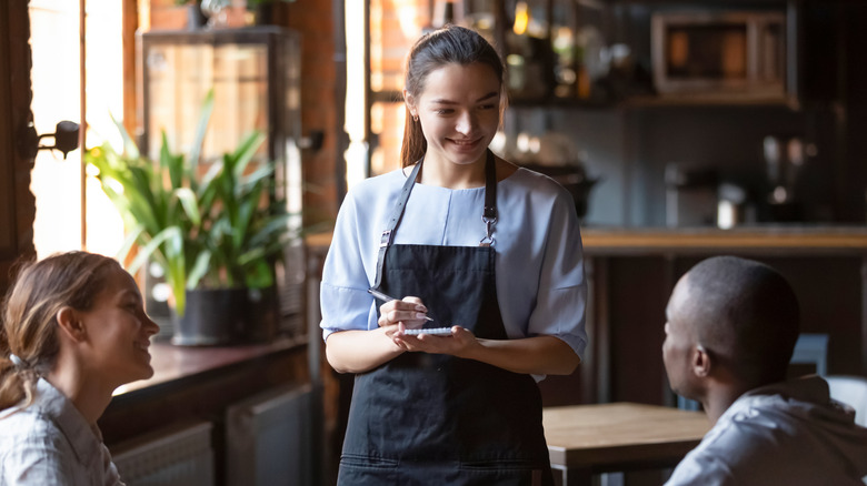a server speaking to a two-person table at a generic restaurant