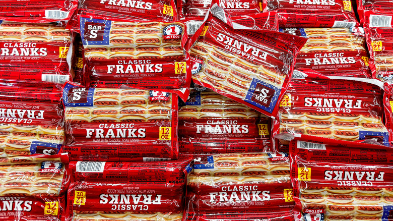 Piles of Bar S sausages in a grocery store meat case.