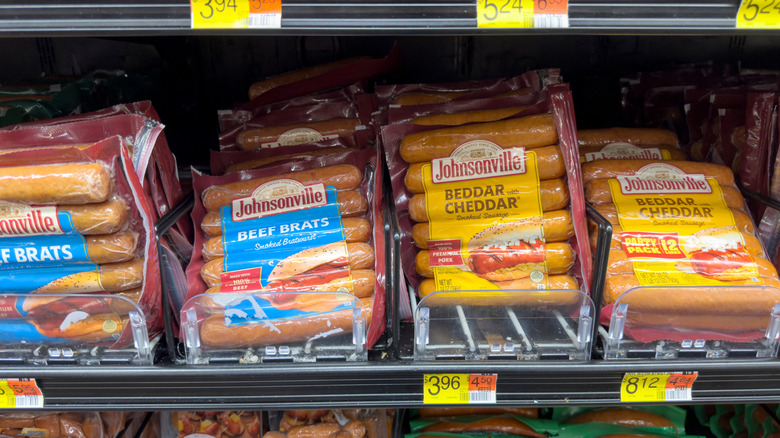 Various Johnsonville sausages sit on a grocery store shelf.