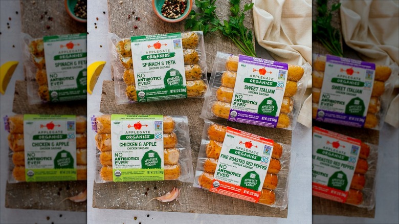 Four varieties of Applegate sausages sit on a wood cutting board.