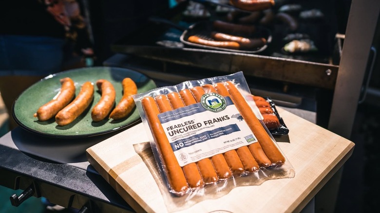 A package of Niman Ranch band uncured franks sits next to freshly grilled sausages.