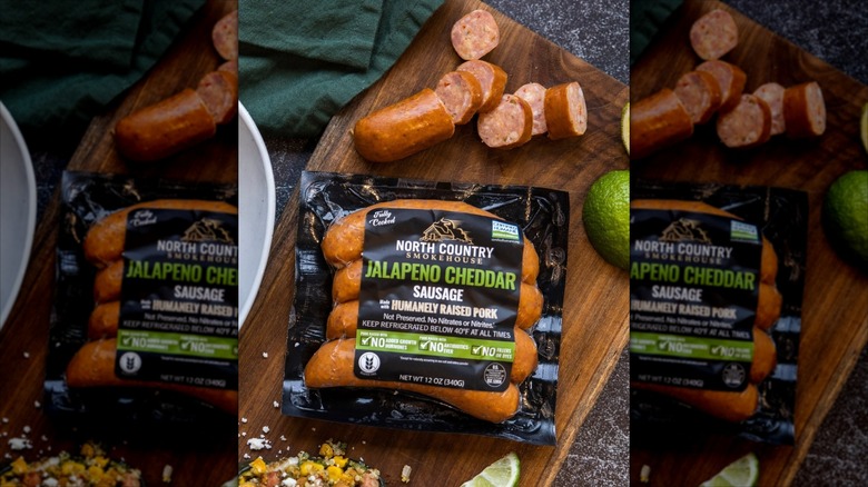 A pack of North Country Smokehouse sausages on a wood background, next to cut-up sausages.