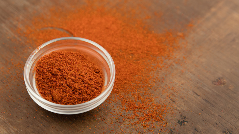 Ground cayenne in a bowl and scattered on a countertop