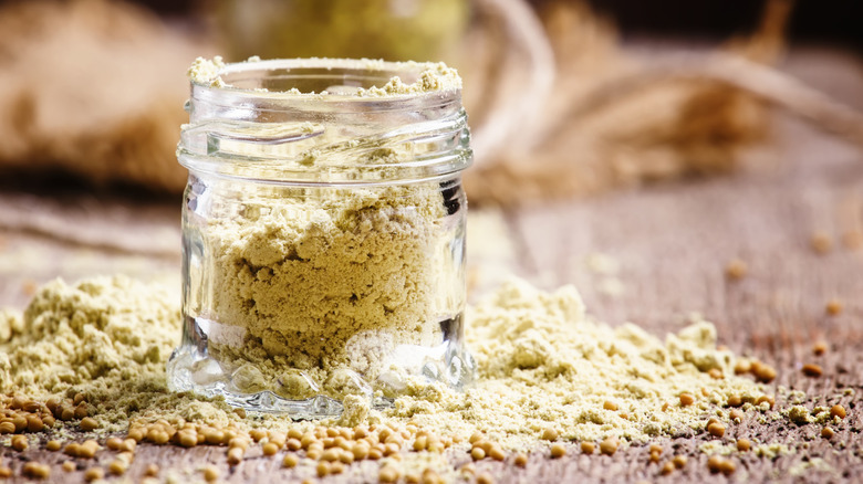 A glass jar full of ground mustard seeds