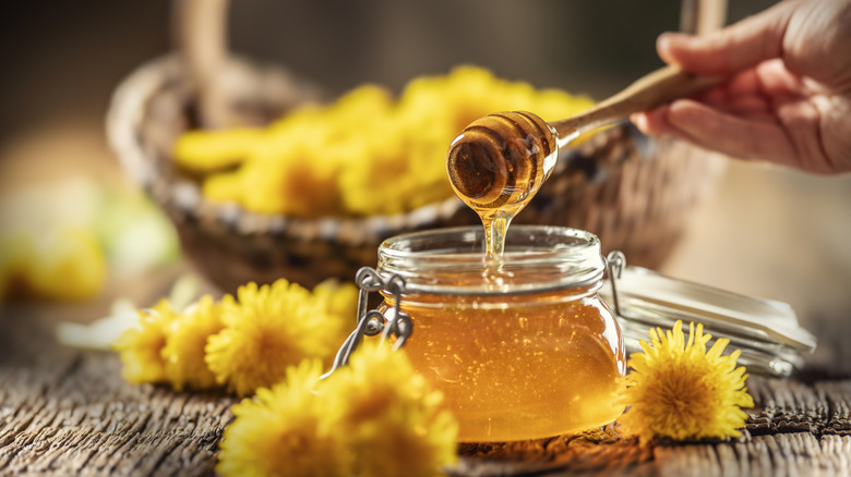 A jar of golden honey dripped from a dipper