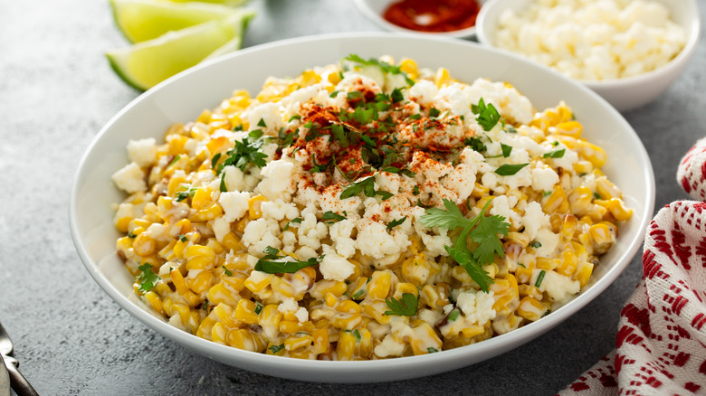 Small white bowl of roasted street corn with cotija cheese and cilantro