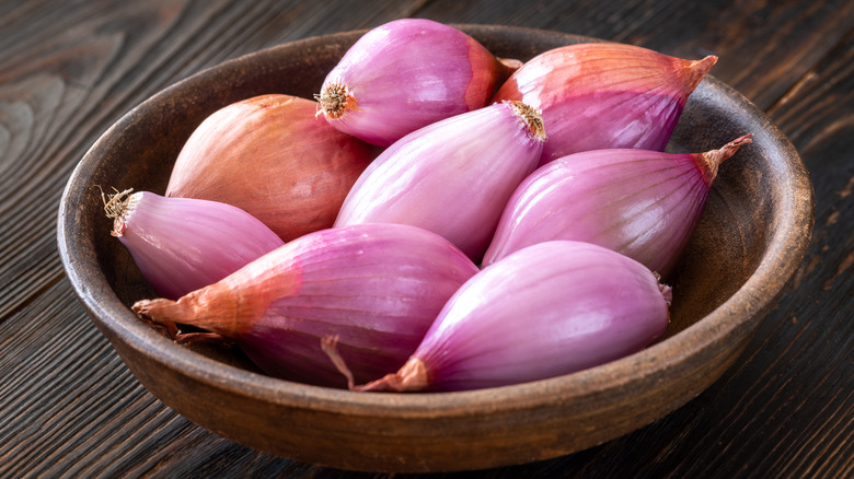 Small wooden bowl full of purple shallots