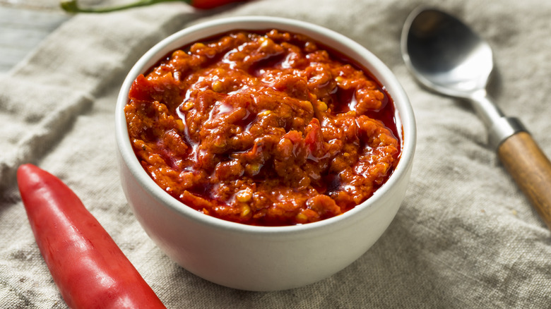 Small bowl of Calabrian chili paste with whole chili and spoon on side