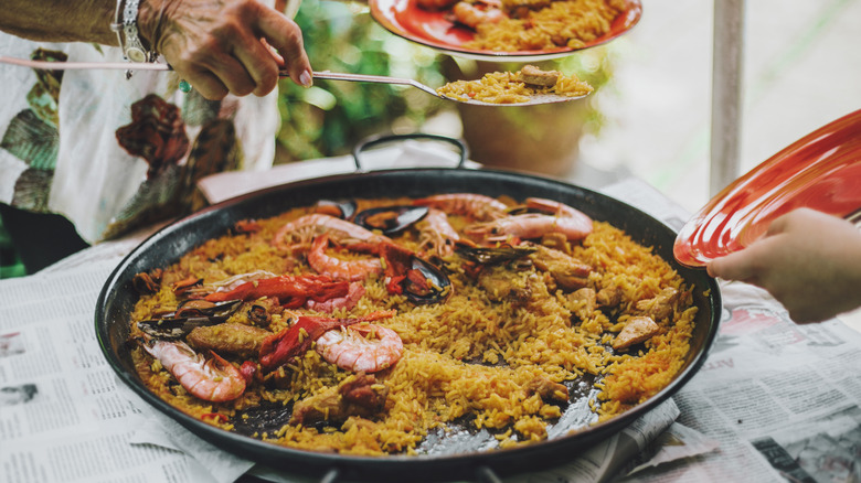 One person serving paella to another person