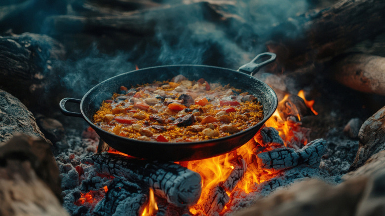 Paella cooking over a crackling campfire