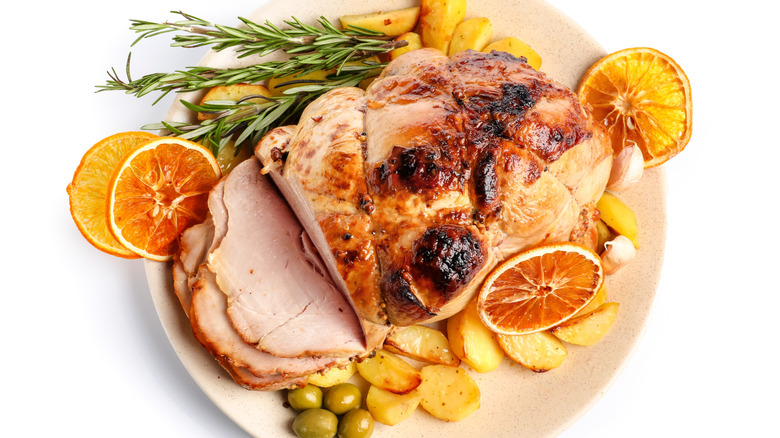 Ham with orange slices, rosemary, and potatoes