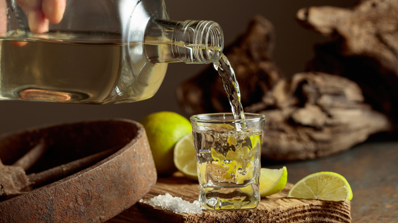 Pouring a shot of tequila with fresh lime wedges and salt