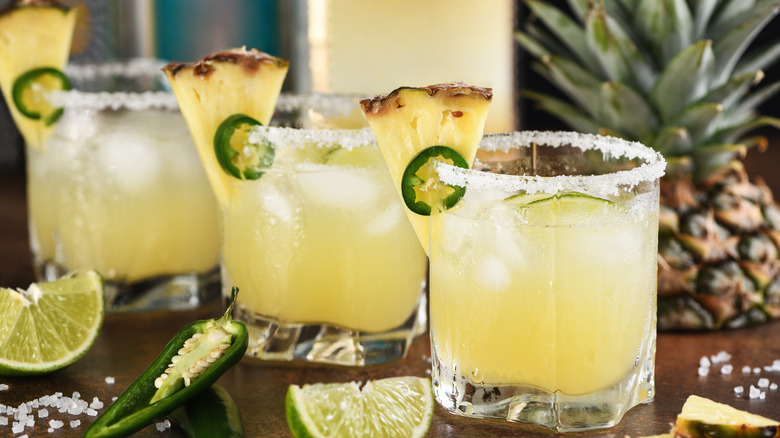 Glasses of iced pineapple soda with fresh pineapple and jalapeno garnishes