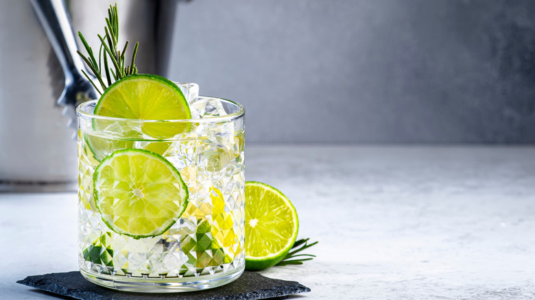 Glass of tonic water with lime wheels and a rosemary sprig