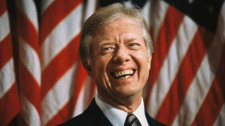 President Carter smiling in front of American flags