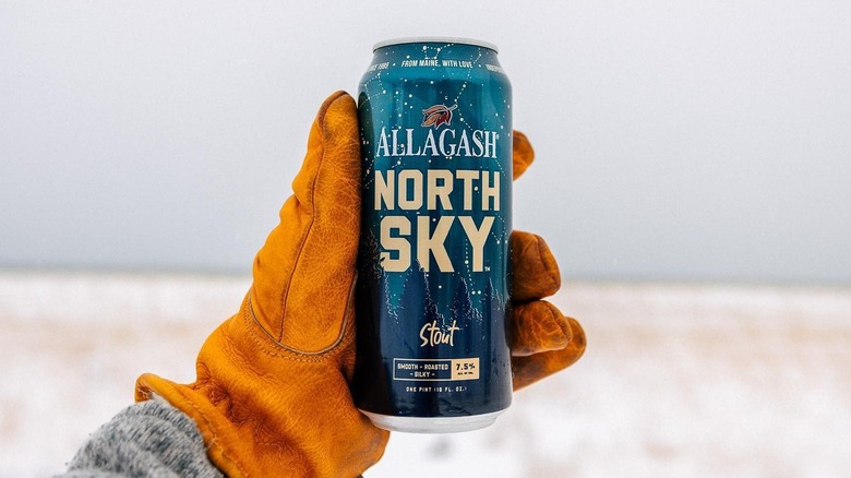 Gloved hand holding can of Allagash North Sky in a snowy setting