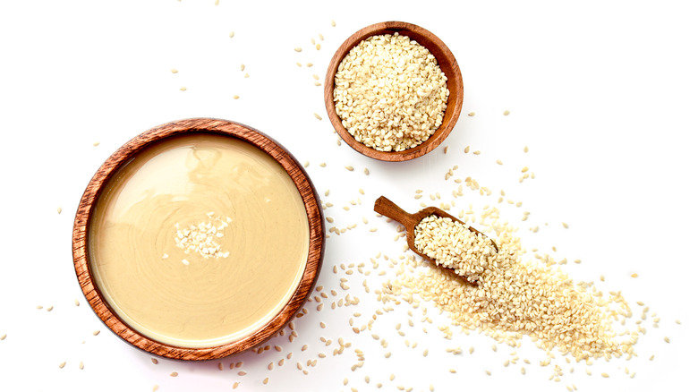 Wooden bowl of tahini on a white background