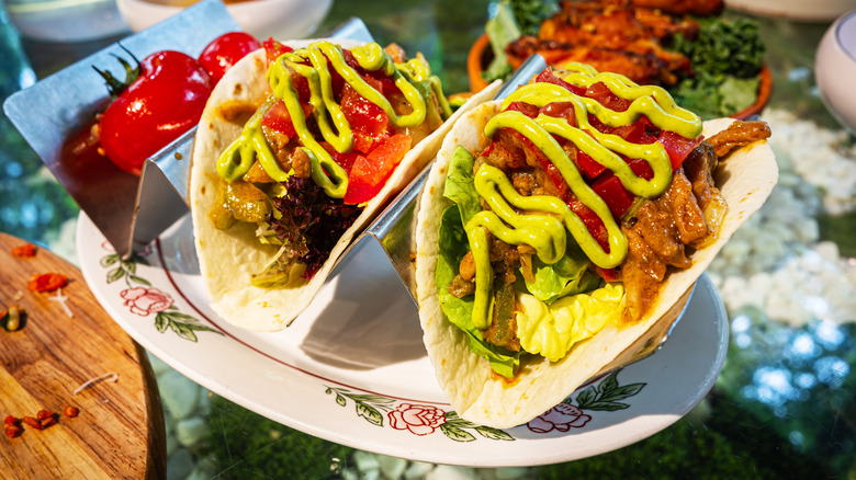 Two very full beef tacos with guac drizzled on top