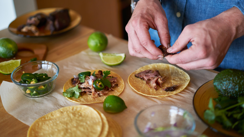 A mans hand assembling tacos