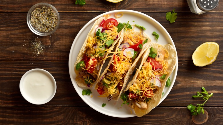 Three tacos with shredded cheese on top