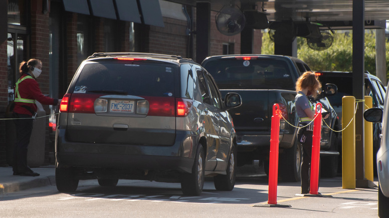 Employees interacting with customers lined up for Chick-fil-A drive-thru