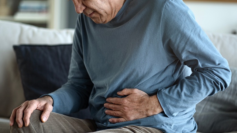 senior man holding his abdomen in pain