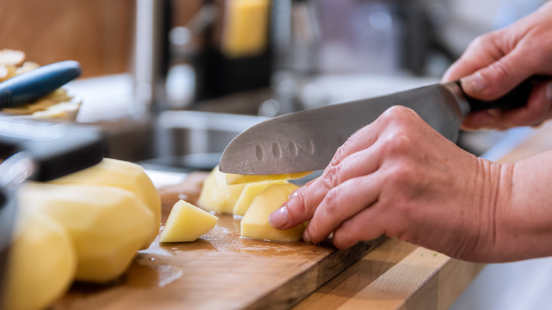 Cook cutting potatoes into chunks