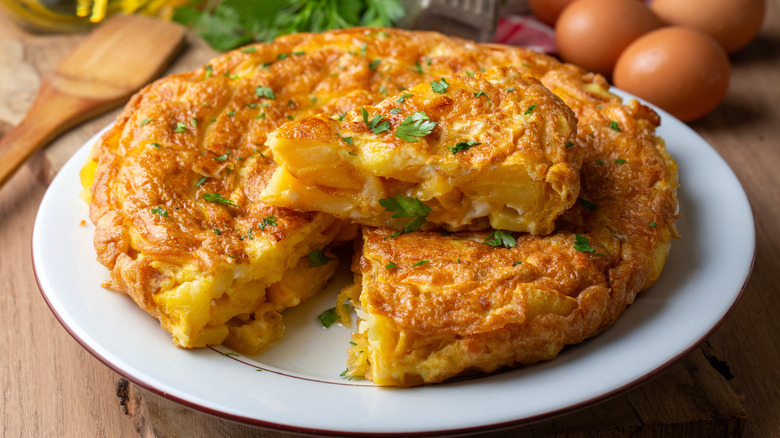 A Spanish omelet, called a Tortilla Espanola, sits on a white plate