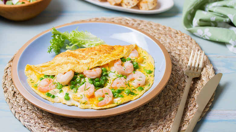 A shrimp, English pea, and herb omelet on a blue plate