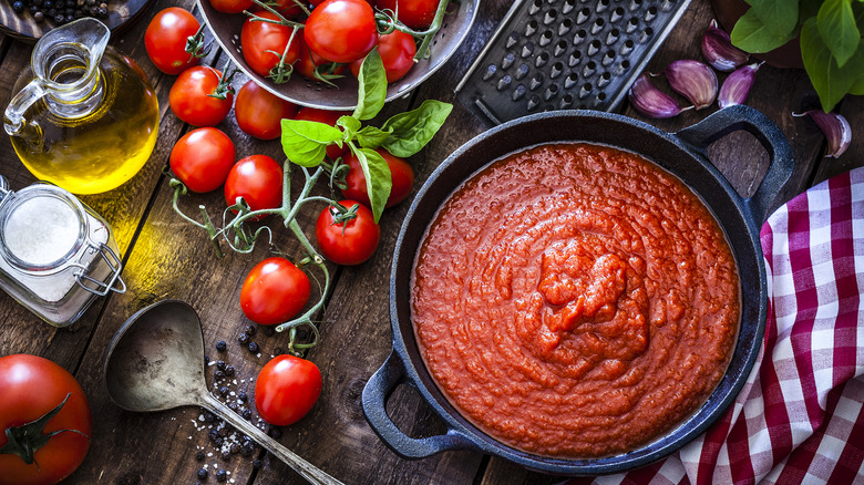 Pot of marinara surrounded by fresh ingredients