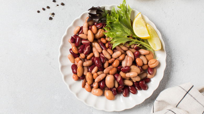 Plate full of mixed beans with lemon wedges