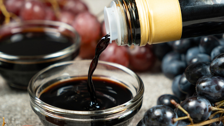 Pouring balsamic vinegar from bottle into glass ramekin