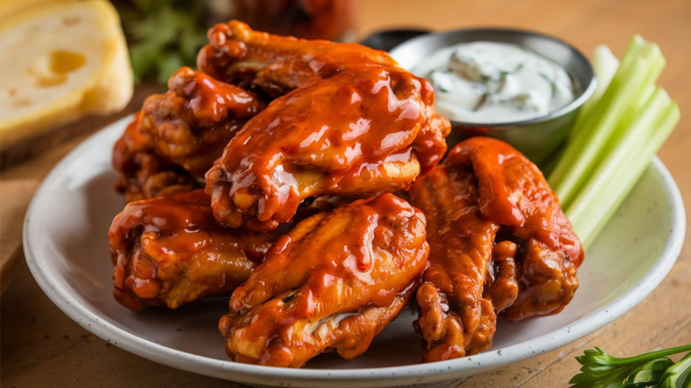 Plate of buffalo chicken wings with dipping sauce and celery