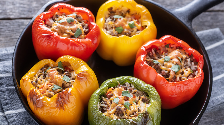 bell peppers stuffed with ground meat and cheese in a cast-iron skillet