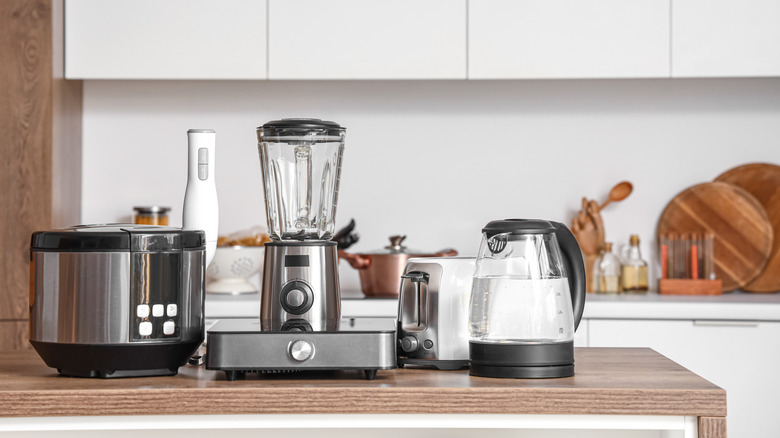 A selection of kitchen appliances sit grouped together on a wooden counter