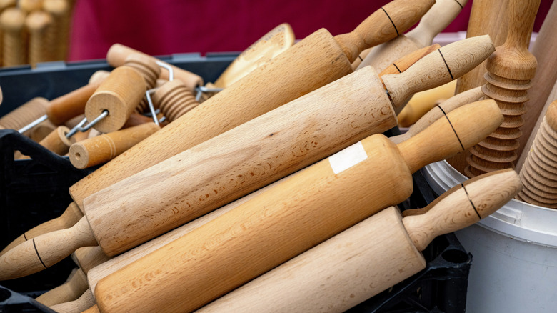 Rolling pins are stacked together in a bin