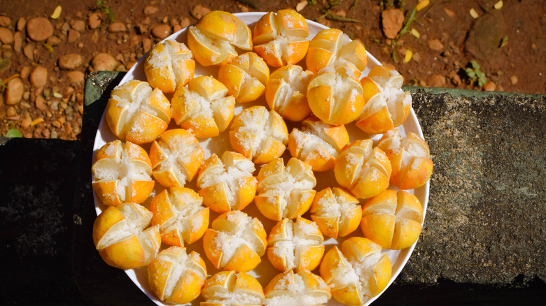 A tray of preserved lemons covered in salt on a stone ledge