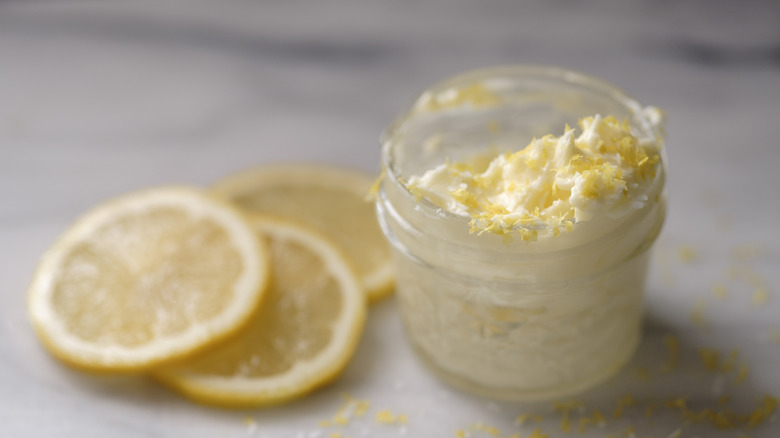 Lemon slices sit beside a small jar of butter with lemon zest