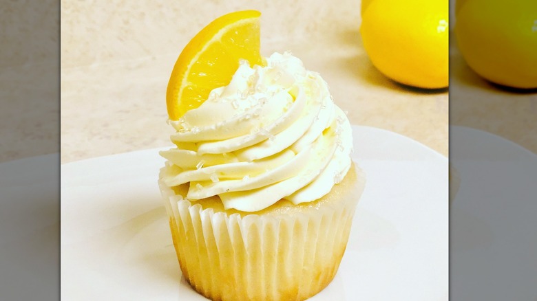 A lemon cupcake with lemon icing and a lemon slice