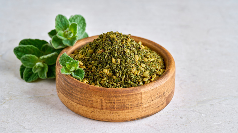 Za'atar in a wooden bowl with wild thyme behind it
