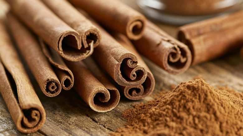 Some cinnamon stick with ground cinnamon on a wooden surface
