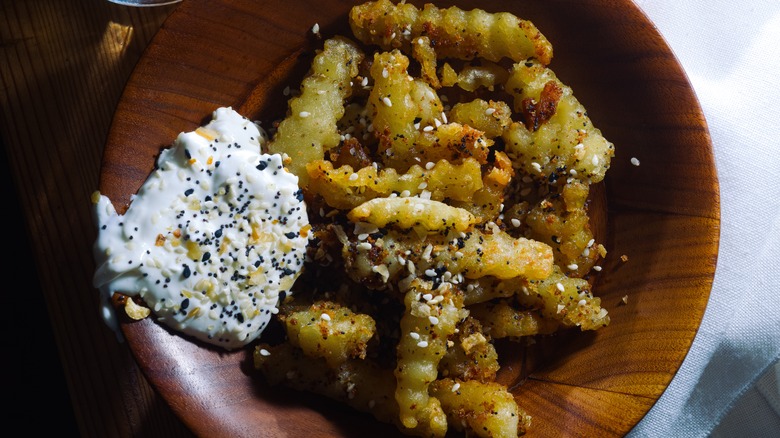 French fries sprinkled with everything bagel seasoning on a wooden plate