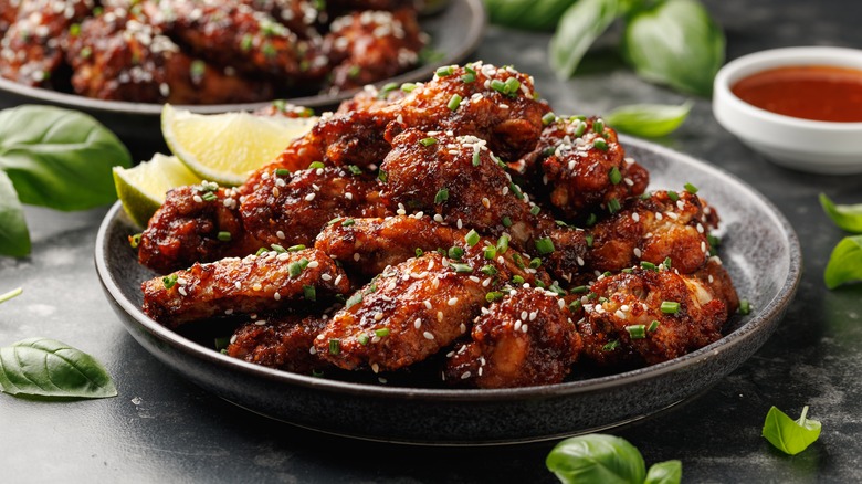 Plate of chicken wings with seeds and diced chives sprinkled on top