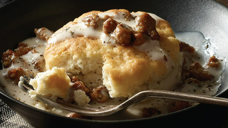 The contents of a Jimmy Dean Biscuit & Sausage Gravy Breakfast Bowl in a black dish with a fork.