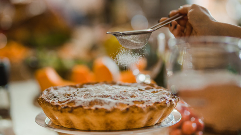 Powdered sugar being sprinkled on a pie
