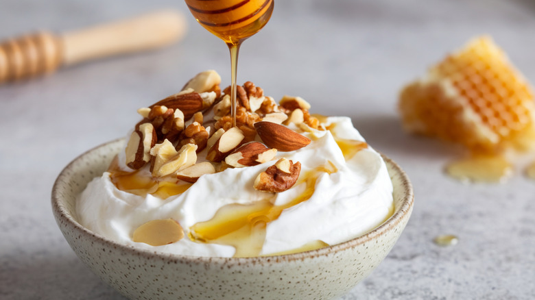 A bowl of yogurt topped with almonds and drizzled honey